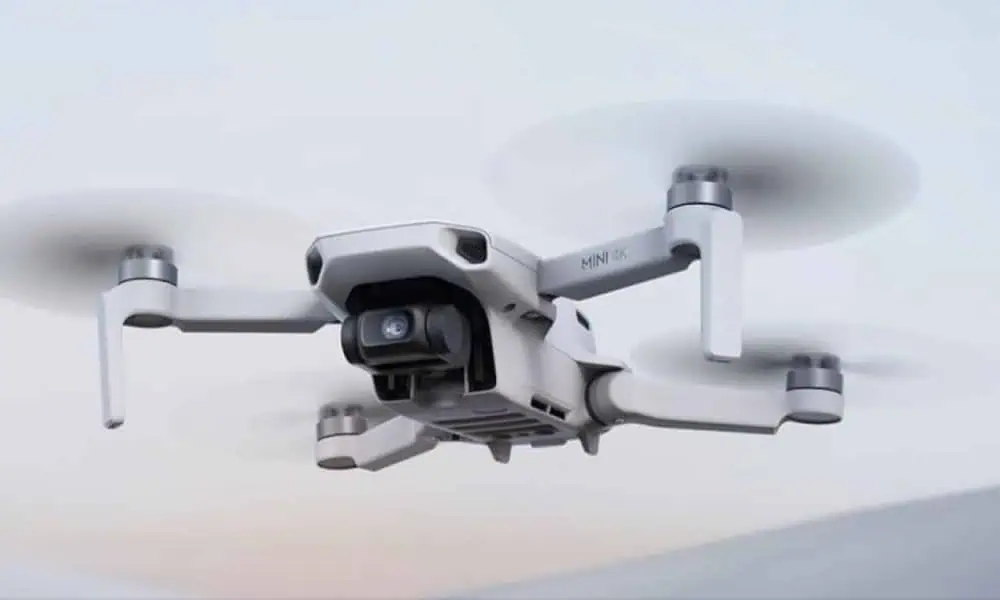 White mini 4K camera drone flying, soft background