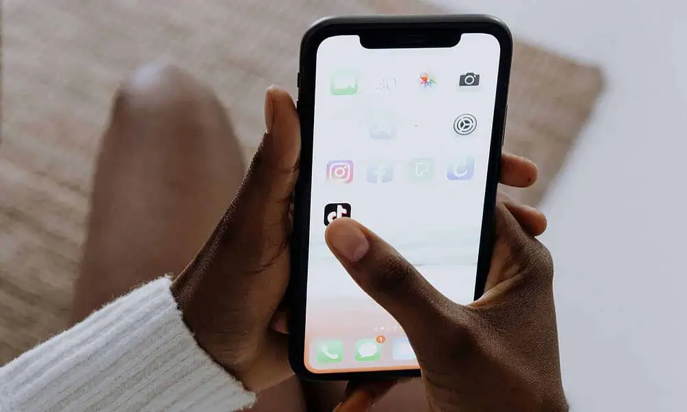 Person holding smartphone with app icons visible.