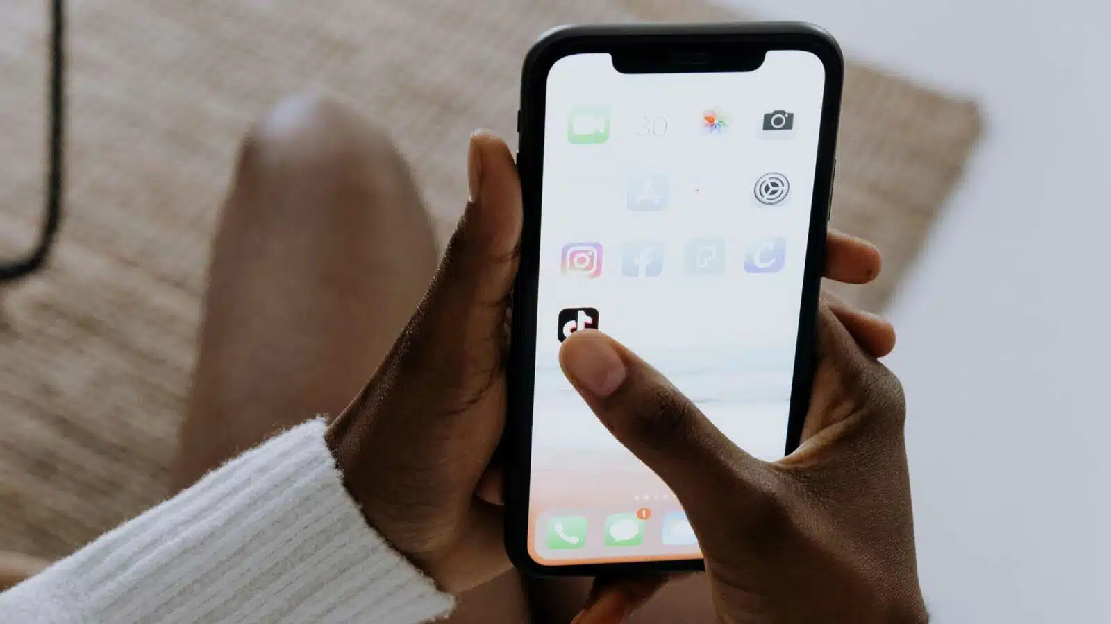 Person holding smartphone with app icons visible.