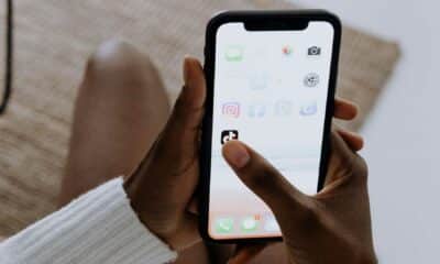 Person holding smartphone with app icons visible.