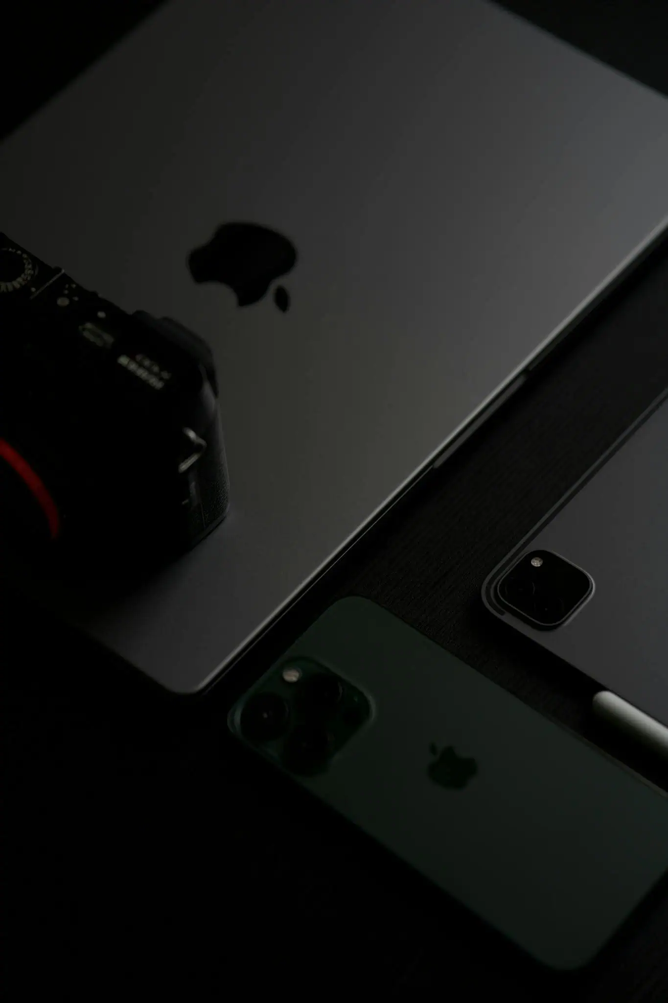 Close-up of electronic devices including a laptop, smartphone, and camera.