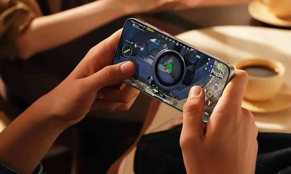 Person playing mobile game with coffee nearby.