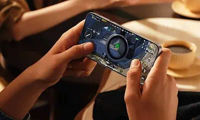 Person playing mobile game with coffee nearby.