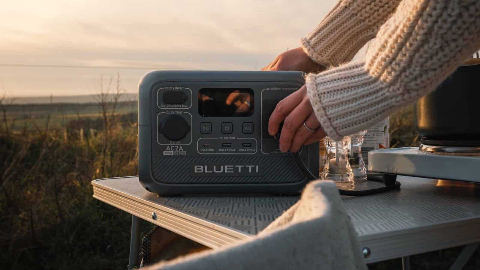 Person operating portable power station outdoors at sunset. AC2A Power station