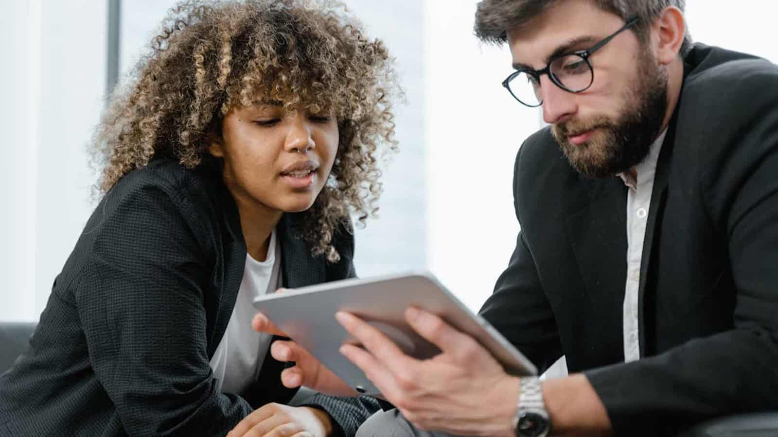 Two people discussing over a tablet.