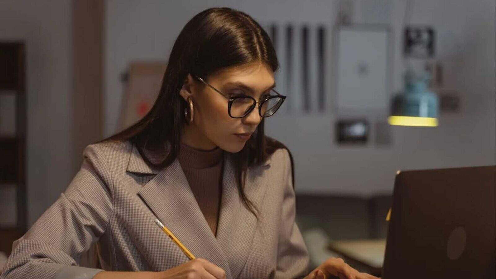 Woman in glasses focused on her laptop work.
