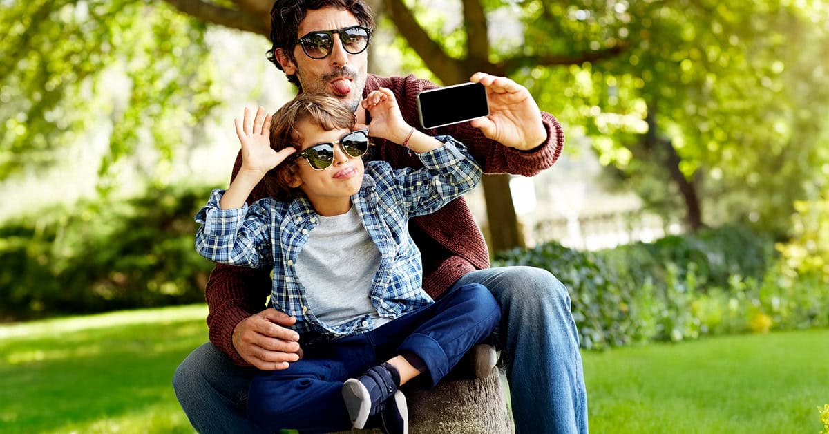 Father and son taking a playful selfie outdoors.