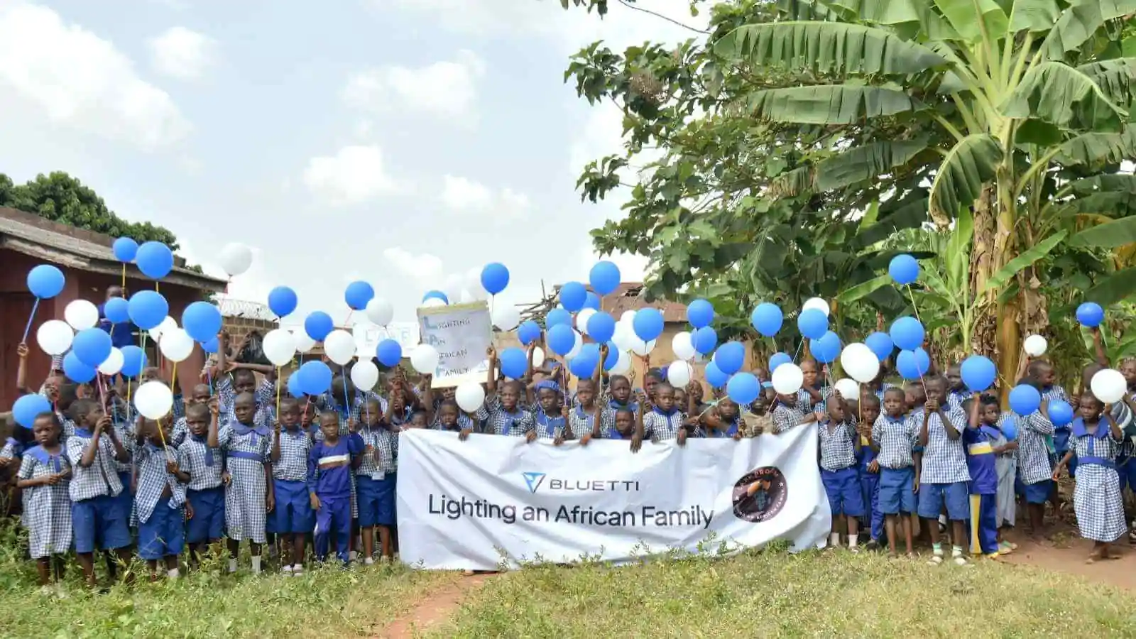 Children with balloons and banner at event.