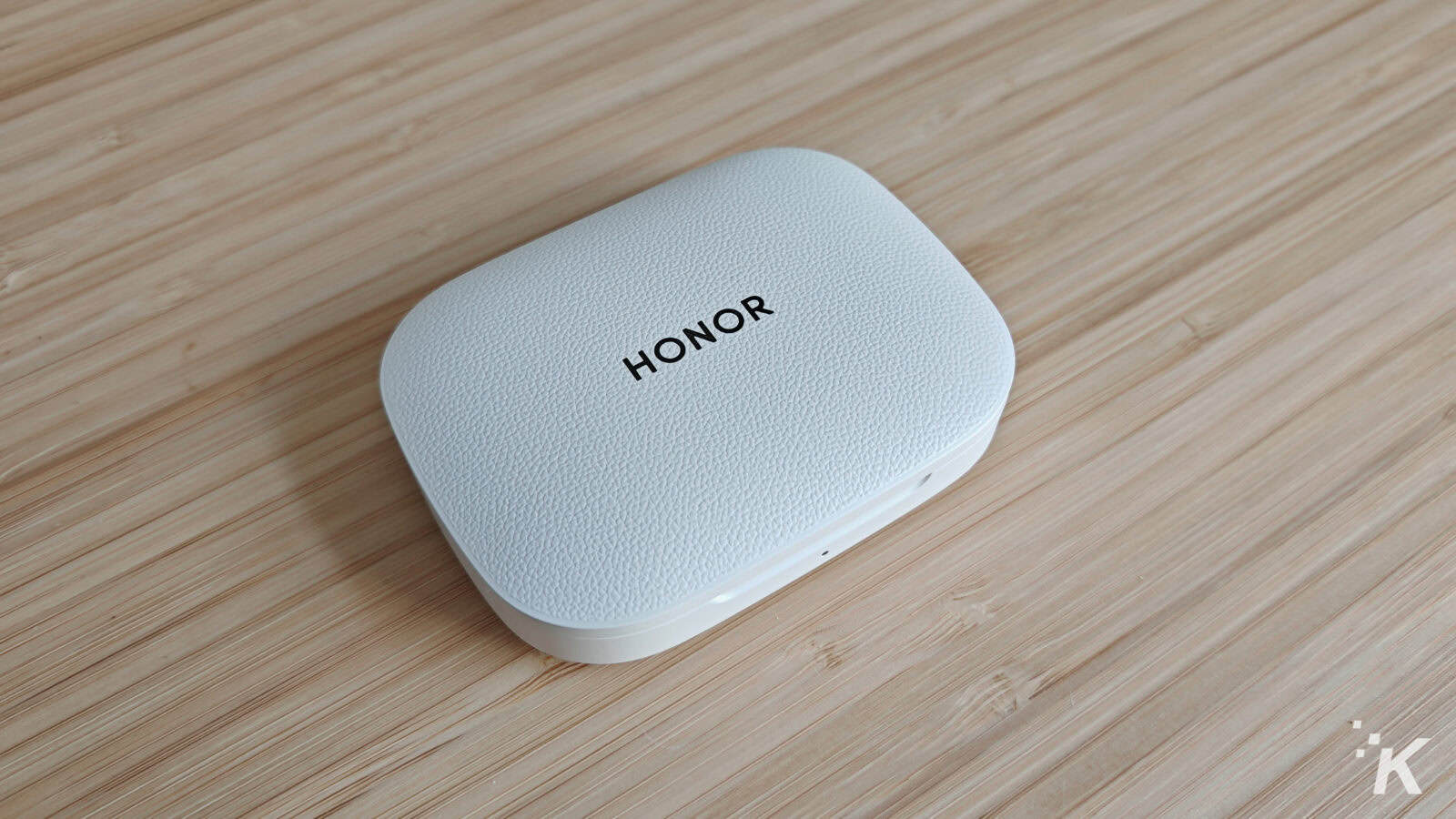 White Honor earbuds case on wooden surface