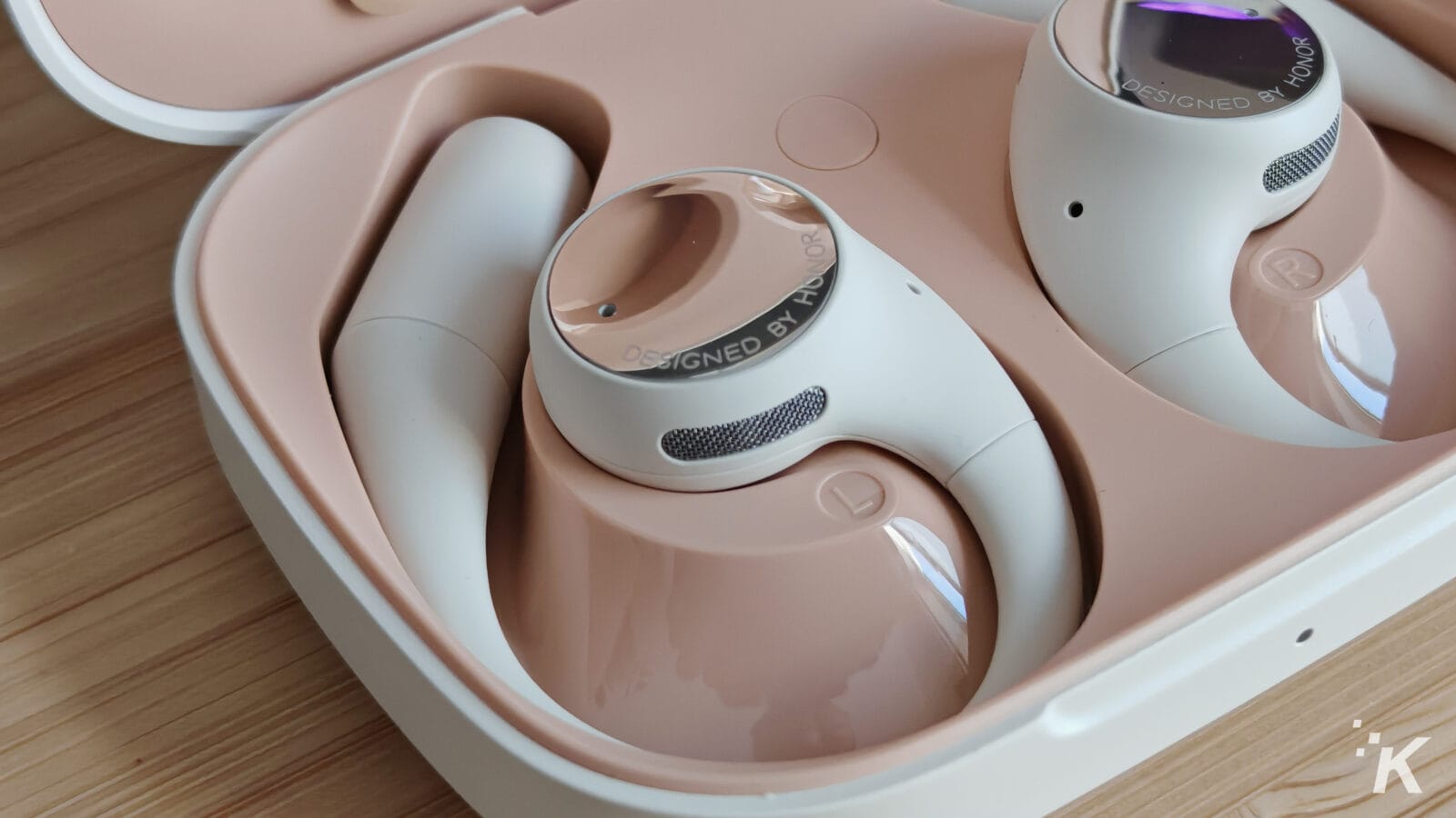 Wireless earbuds in charging case on wooden table.