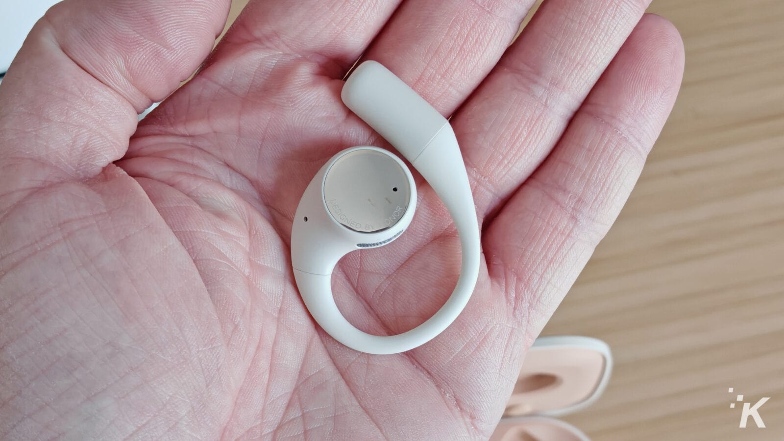 White wireless earbud in hand close-up