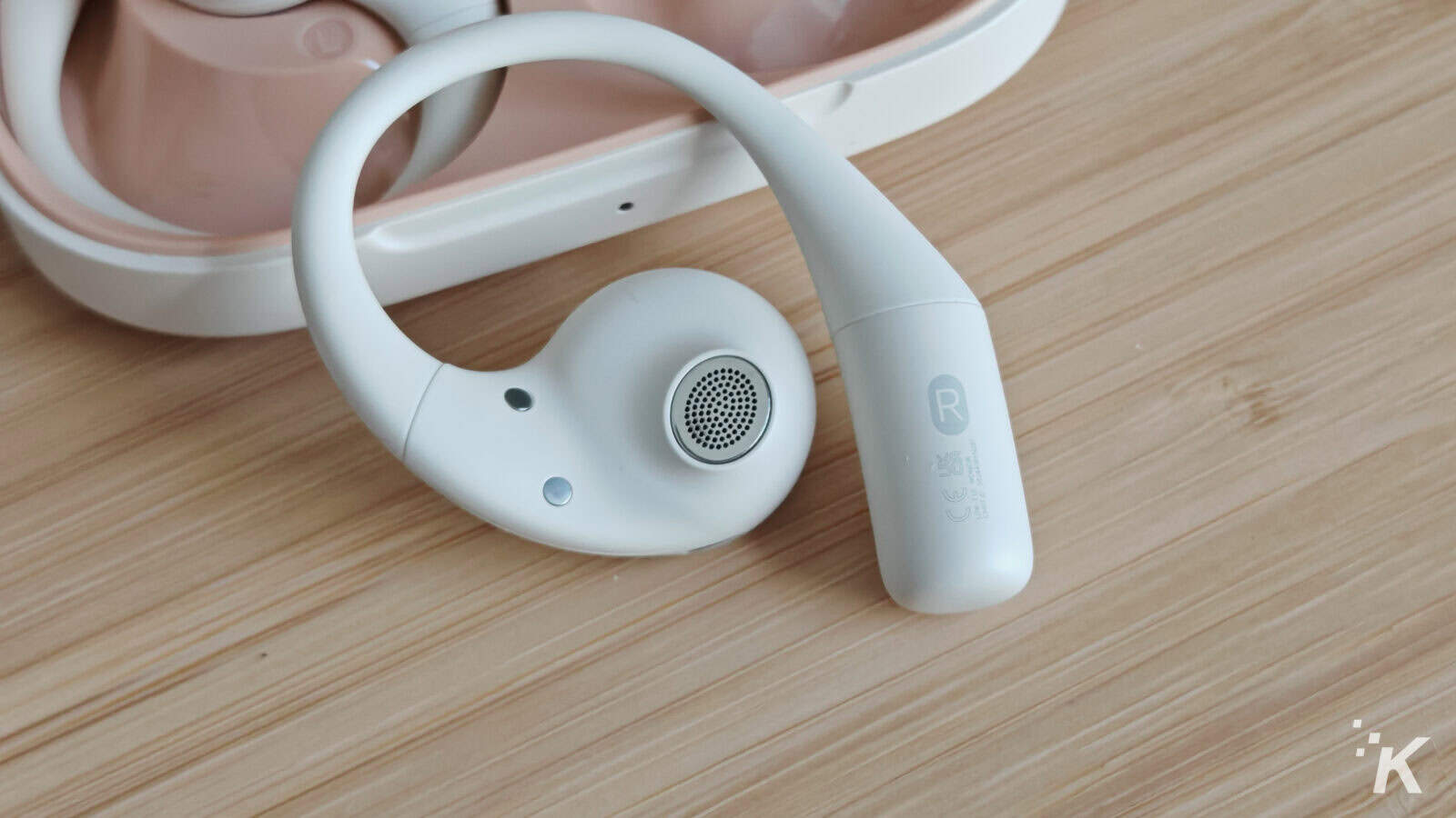 Close-up of white wireless earbud with case.