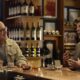 Two men talking in a bar with drinks.