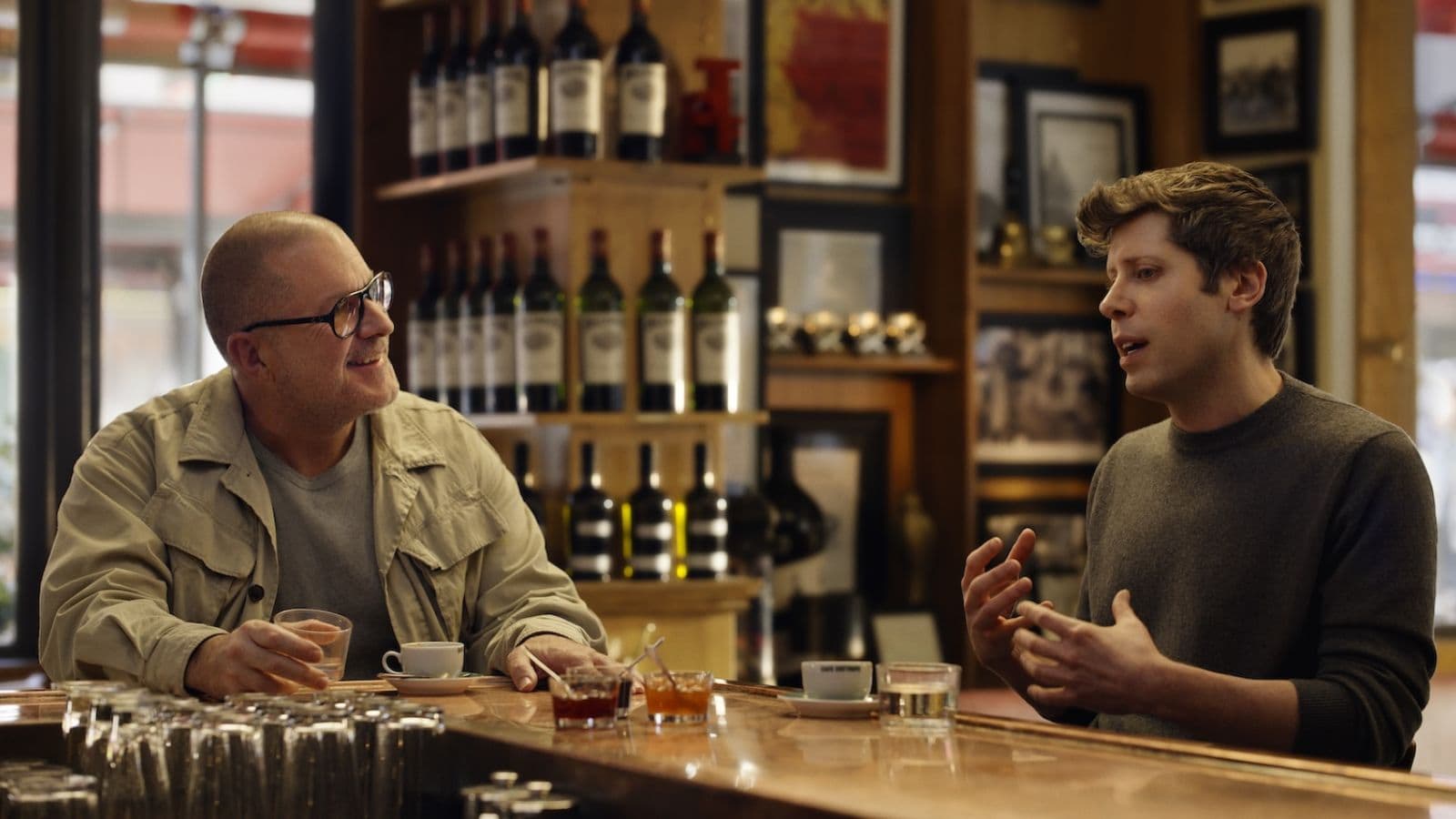 Two men talking in a bar with drinks.