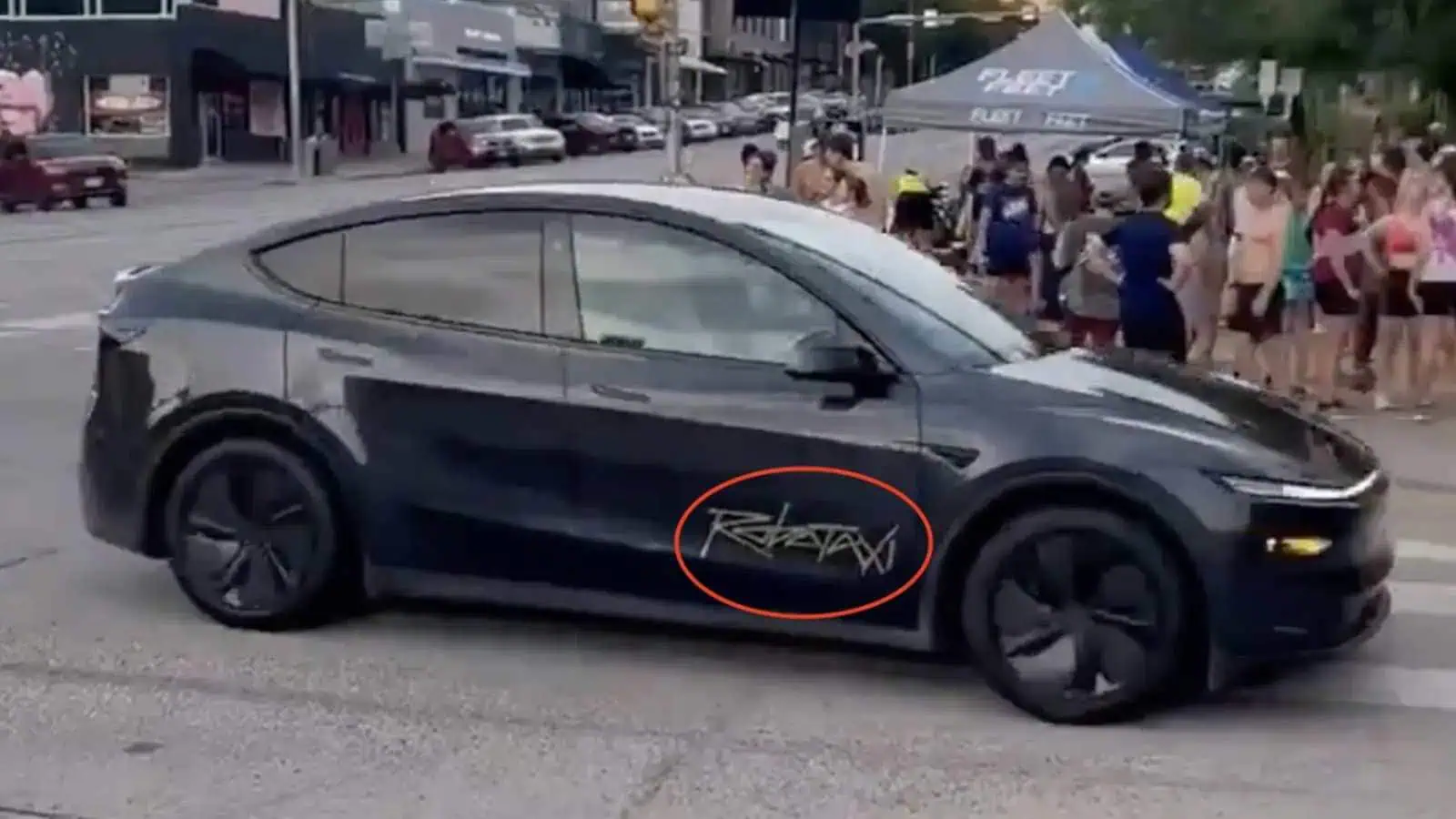 Black car with unique side graffiti on street.
