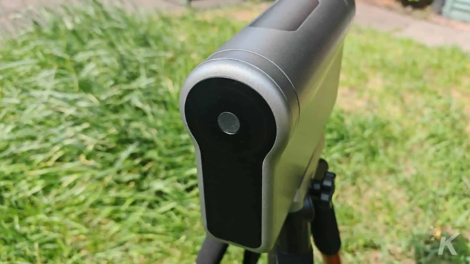 Modern telescope on tripod in grassy area.