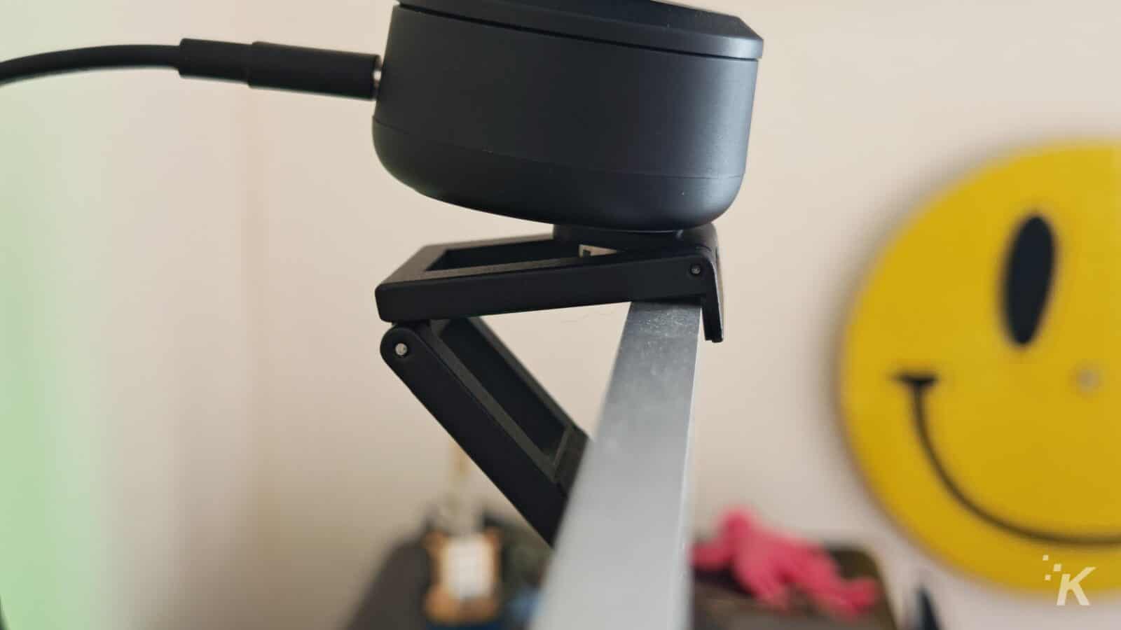 Black device mounted on metal stand with smiley backdrop.