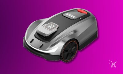 Smart robotic lawn mower on pink background.