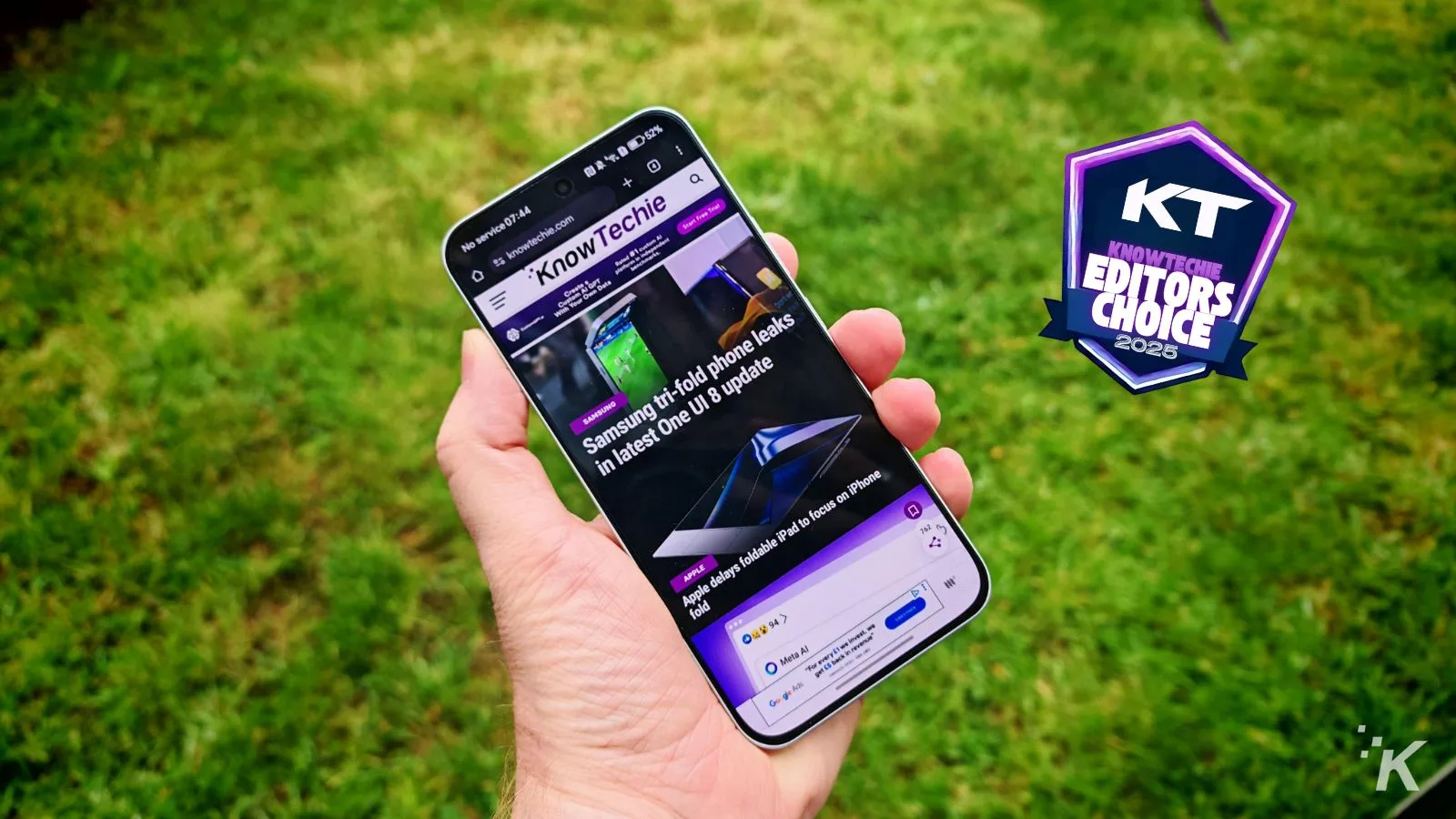 Hand holding smartphone with KnowTechie article displayed.