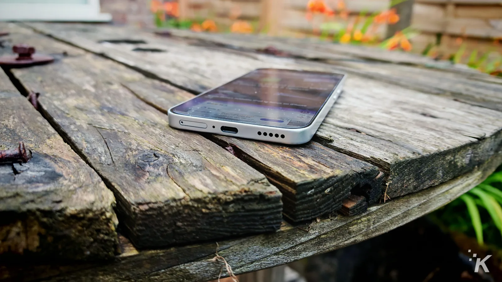 Smartphone on rustic wooden table outdoors.