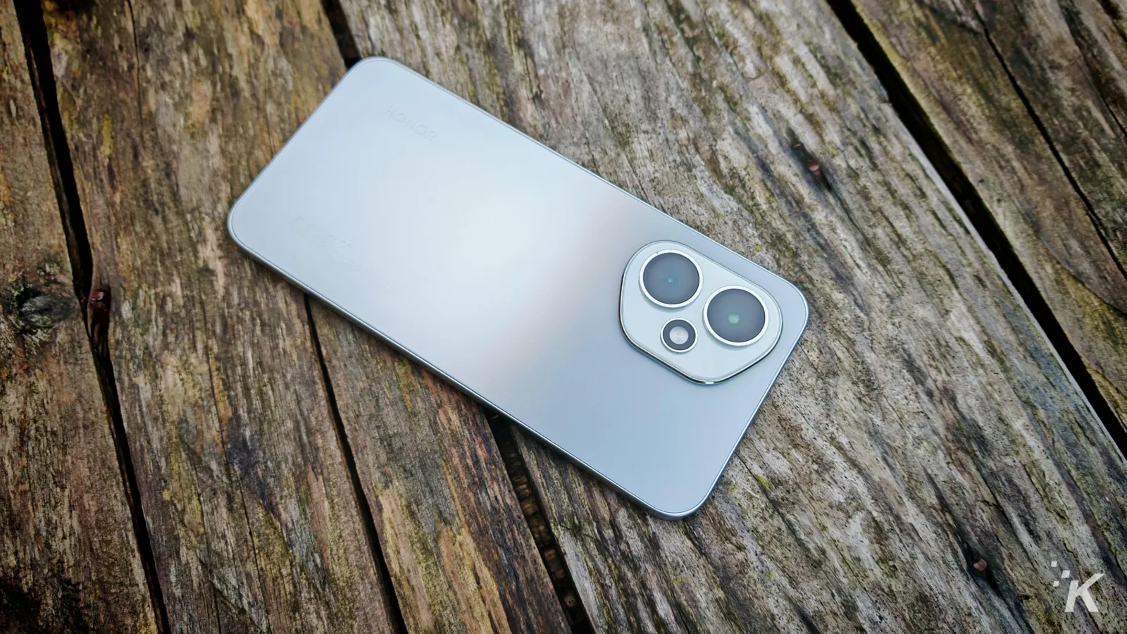 Silver smartphone on wooden surface.