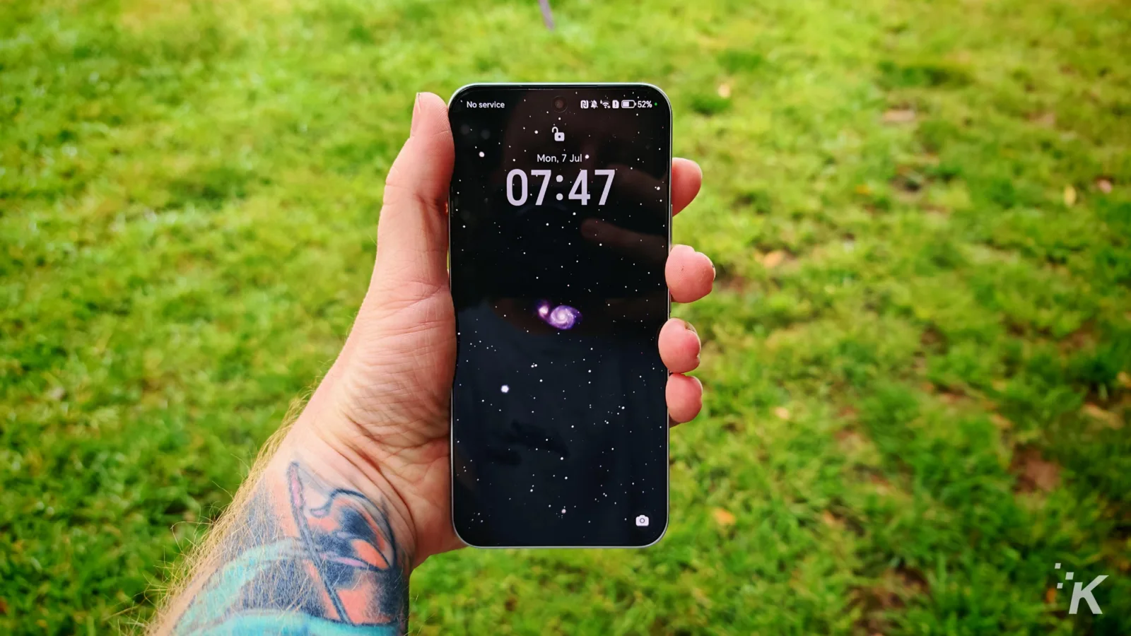 Hand holding smartphone with space-themed lock screen.