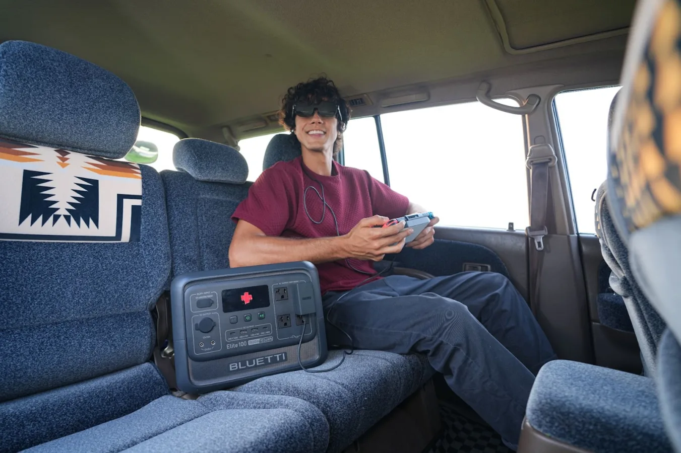 Person gaming with Bluetti power station in vehicle.