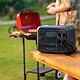 Portable generator on outdoor table for backyard barbecue.