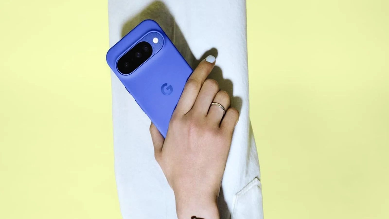 Hand holding blue smartphone, yellow background