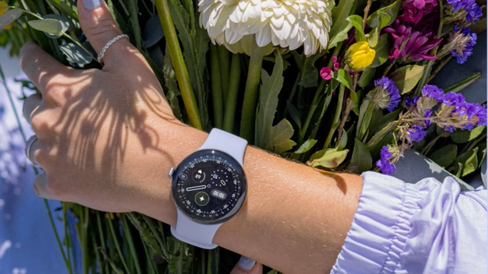Smartwatch on wrist holding colorful flower bouquet.
