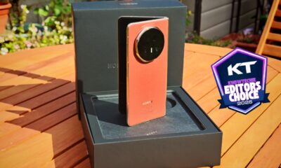 High-end Honor smartphone with a distinctive circular camera module, presented outdoors on a wooden table, showcasing innovative mobile device design and cutting-edge technology.