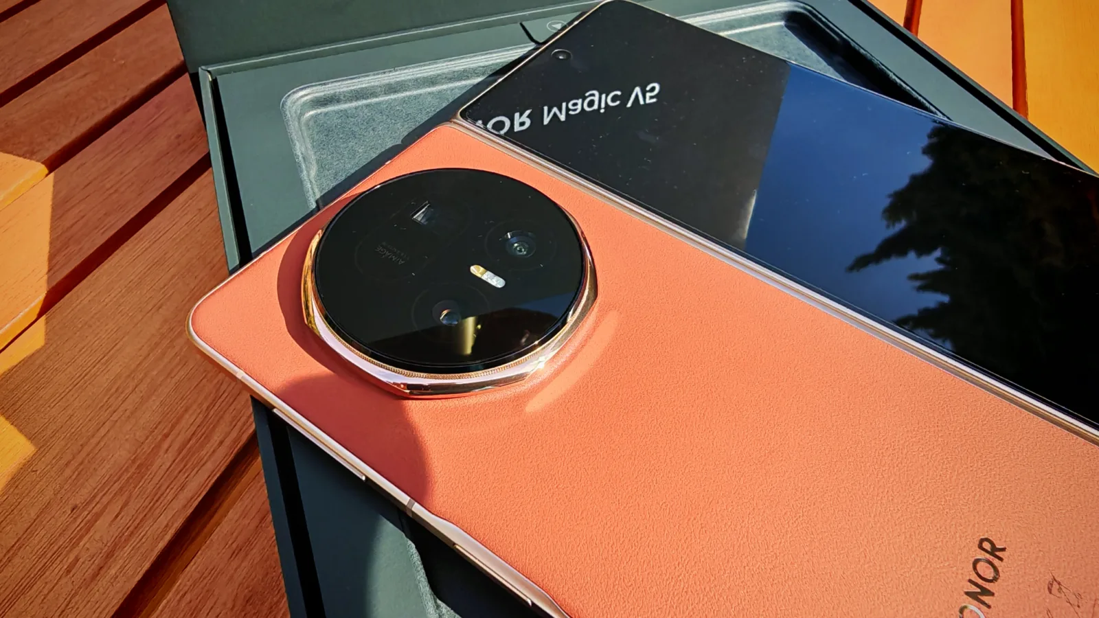 High-quality smartphone with large camera lens on orange back, placed on wooden surface, showcasing advanced mobile photography features.