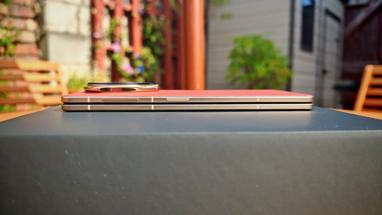 Stacked smartphones and a smartwatch on a table outdoors during daytime.