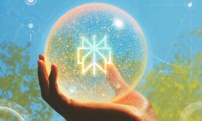 Hand holding glowing sphere against sky background.
