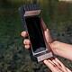 Futuristic smartphone stored in a sleek, metallic case held by a person outdoors near water.