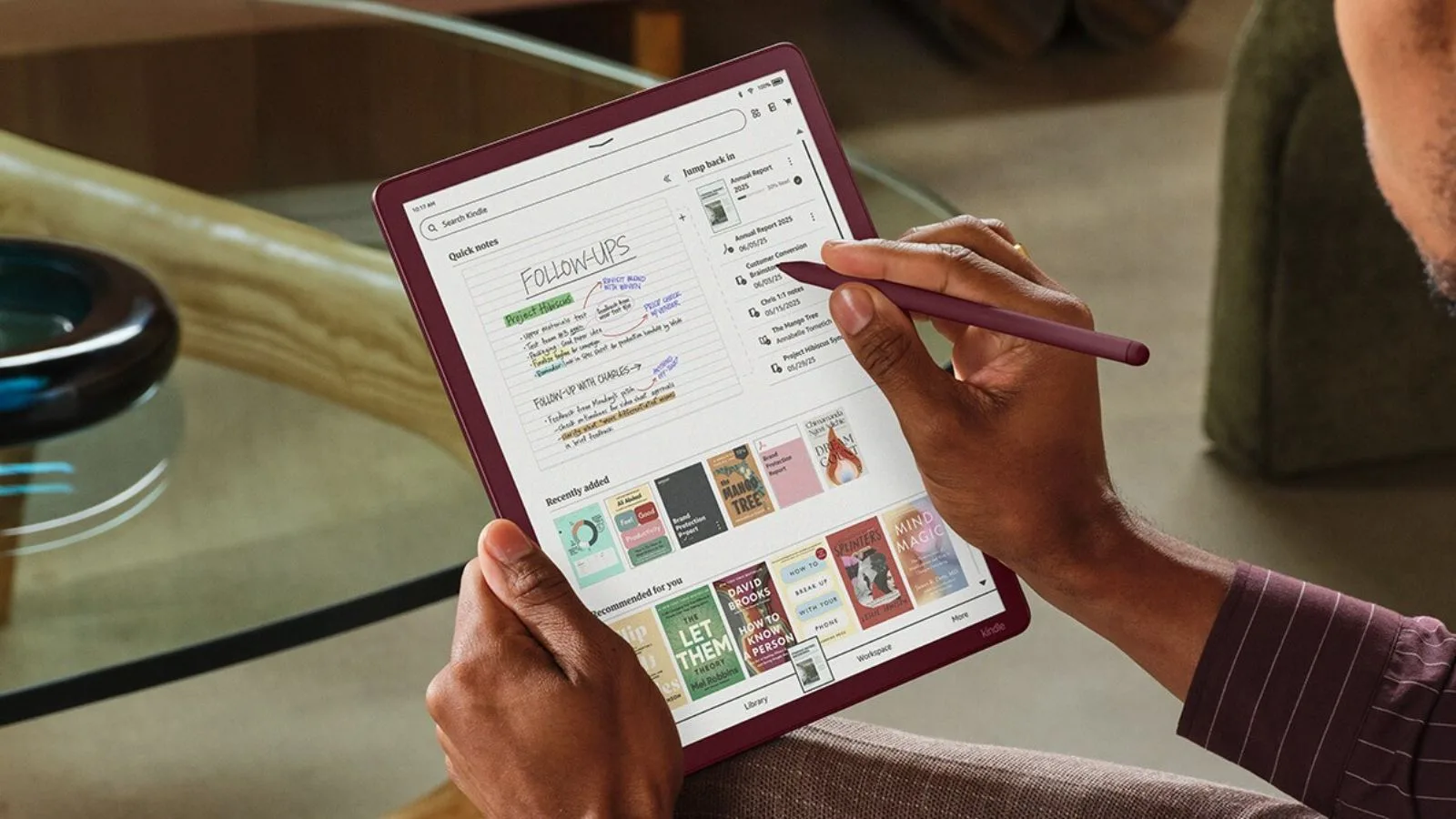 A person using a Kindle tablet with a stylus, organizing notes and books, showcasing digital note-taking and e-reader technology.