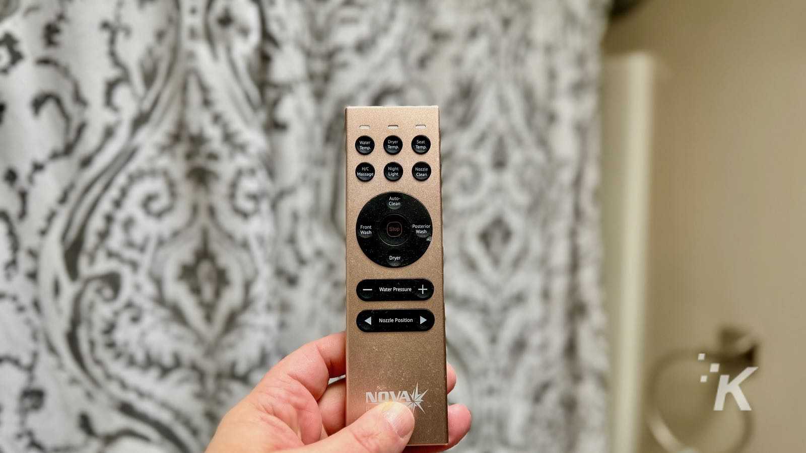Hand holding remote control with various buttons.