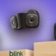 Miniature smart cameras mounted on a wooden shelf, showcasing innovative home security devices from Blink; various models are displayed against a purple gradient background.