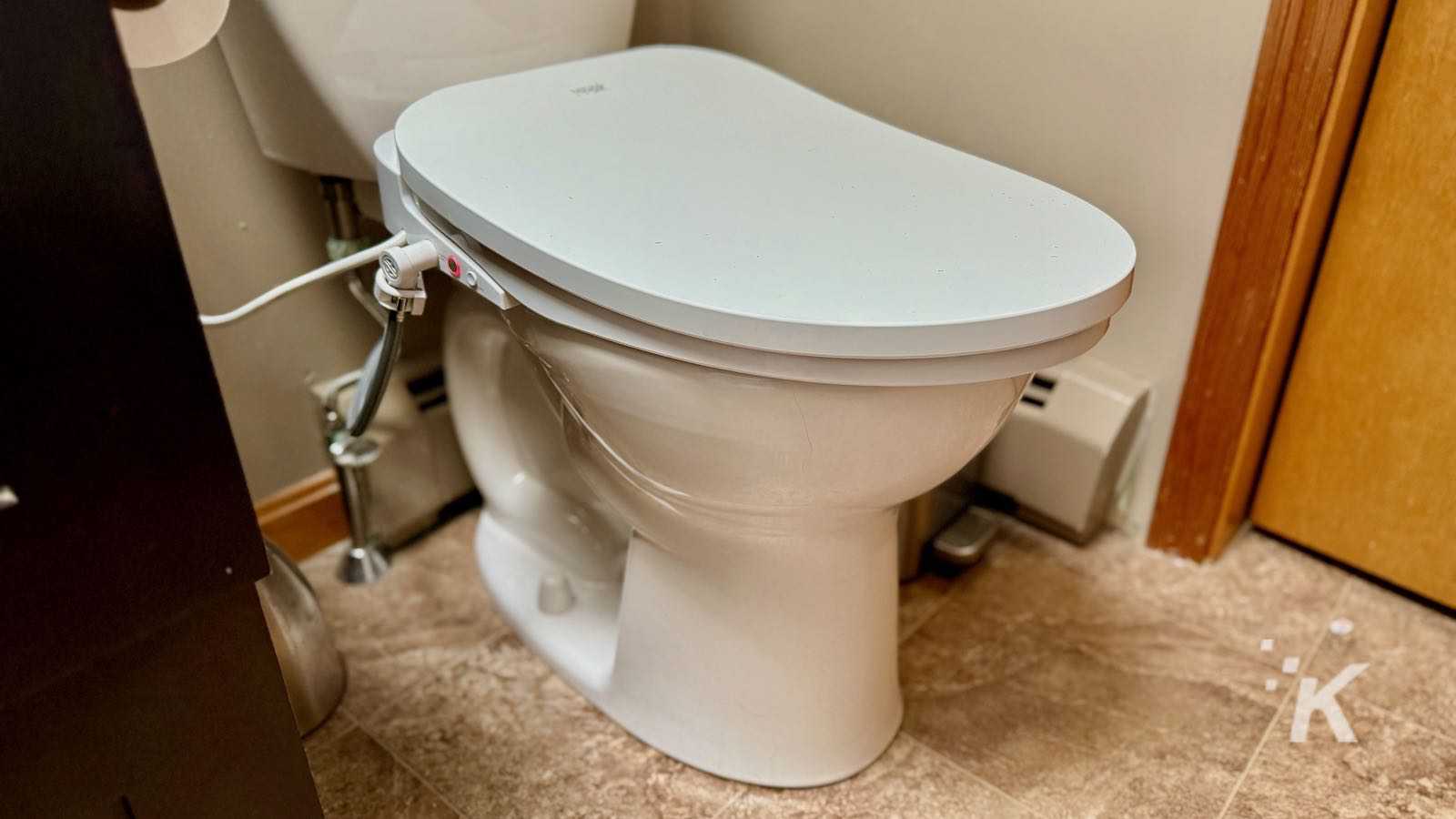Toilet with a smart lid in a bathroom setting, connecting to power for advanced features like automatic lid opening. Modern bathroom technology integrating smart toilet accessories for enhanced hygiene and convenience.