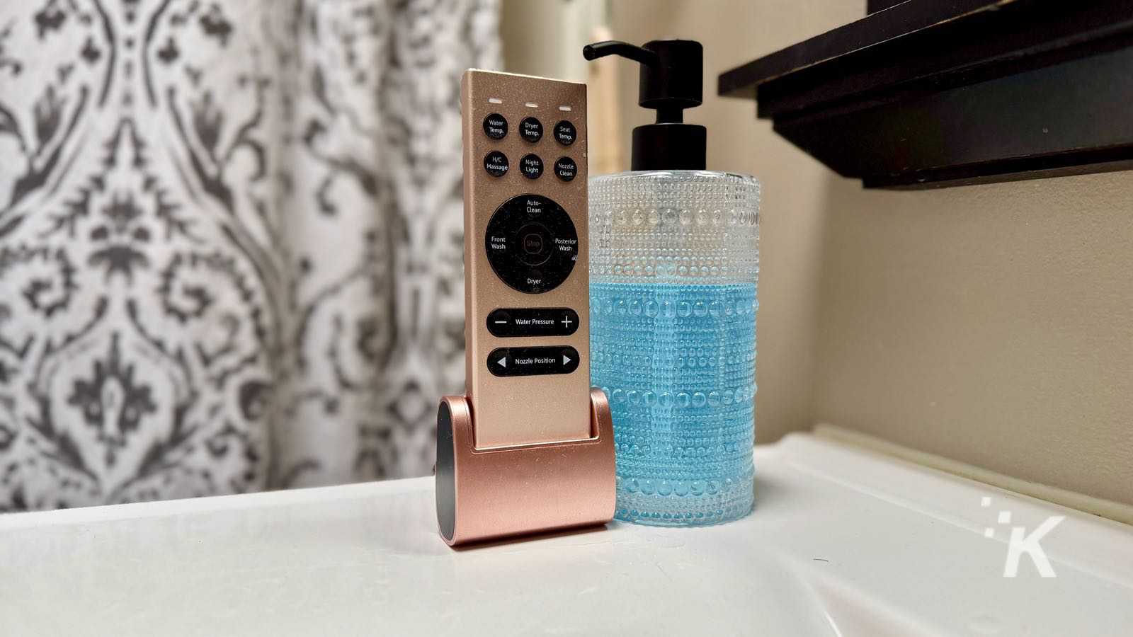 Bidet remote and soap dispenser on bathroom counter.