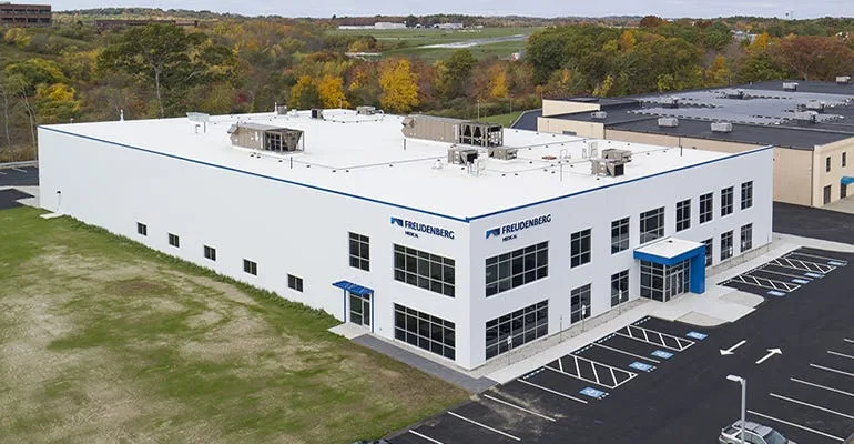 Freudenberg industrial building with parking and landscape view.