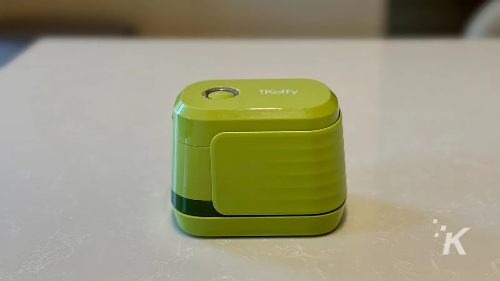 Green portable coffee maker on white counter.