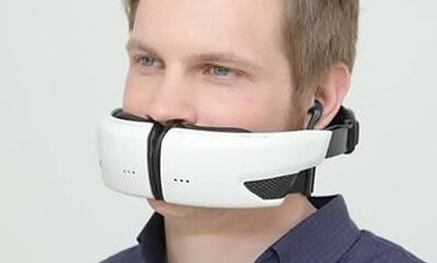 Wireless virtual reality headset for immersive gaming experiences, worn by a young man with blue eyes and short blond hair, connected with earphones for enhanced audio.