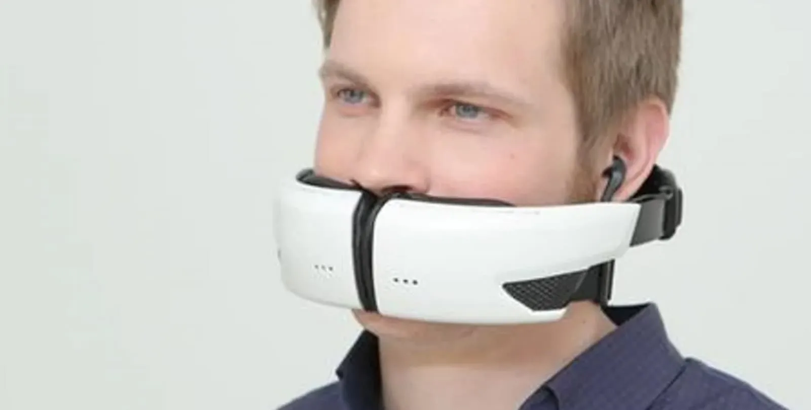 Wireless virtual reality headset for immersive gaming experiences, worn by a young man with blue eyes and short blond hair, connected with earphones for enhanced audio.