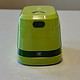 Bright green compact electric pencil sharpener with a black "PRESS" button on top and an "OPEN" compartment at the bottom, placed on a white surface.