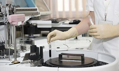 High-tech laboratory scientist handling blood samples using automated medical diagnostic equipment in a medical research facility.