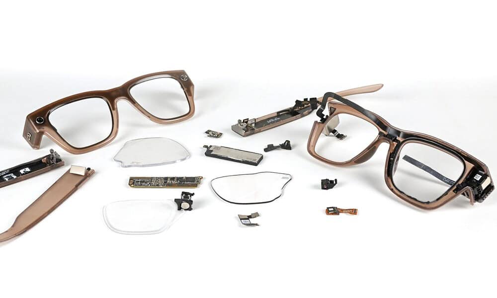 Disassembled smart glasses with electronic components and broken lenses on a white background.