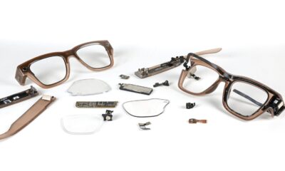 Disassembled smart glasses with electronic components and broken lenses on a white background.
