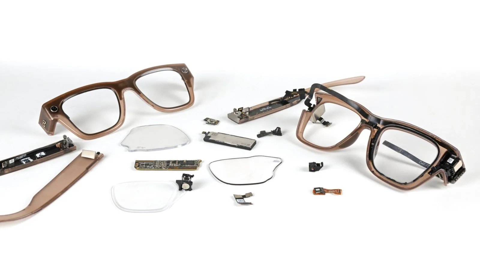 Disassembled smart glasses with electronic components and broken lenses on a white background.