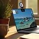 Virtual meeting on a laptop with a nature desktop background, featuring a webcam displaying an elderly man, in a cozy, sunlit home office setting with potted plants.